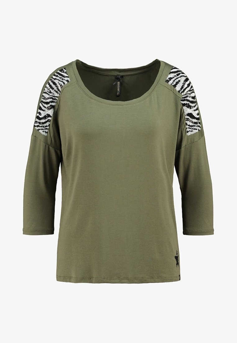 Olivgrünes Hemd mit Dreiviertelärmeln, ausgestattet mit schwarzen und weißen Paillettenakzenten im Zebra-Muster auf den Schultern. Weicher Stoff.