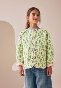 Veste matelassée vert clair avec motifs floraux, passepoil rose et boutons. Comprend deux poches avant et un col arrondi. Texture douce.