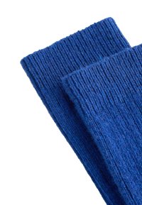 Calze di maglia blu a coste con una finitura testurizzata. Tessuto spesso, design verticale e dettaglio di cuciture visibili.