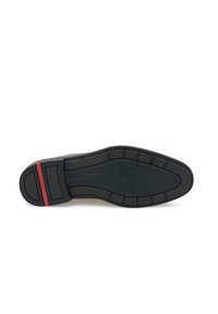 Semelle en caoutchouc noire présentant une surface texturée, des rainures horizontales et une bande d'accent rouge au niveau du talon pour un détail supplémentaire.