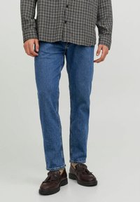Camisa a cuadros en blanco y negro combinada con jeans rectos azules y zapatos marrón oscuro con detalles de borlas.