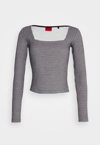 Langärmliges Oberteil aus geripptem Stoff im schwarz-weißen Wiener-Stil, mit quadratischem Ausschnitt und tailliertem Schnitt. Rotes Etikett sichtbar.