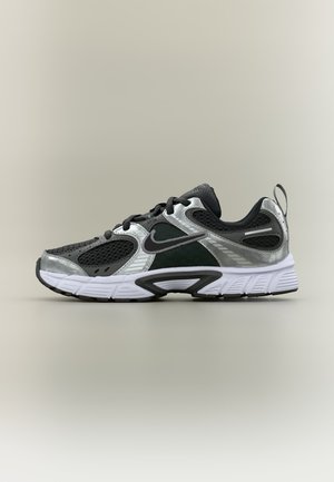 Μαύρο και ασημί παπούτσι τρεξίματος Nike με λευκή σόλα, πλέγμα στα πάνελ και το λογότυπο της Nike στο πλάι, φαίνεται από την εξωτερική πλευρά.