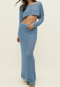 Ensemble deux pièces tricoté bleu clair comprenant un haut court à manches longues et une jupe longue, tous deux avec une texture à maille ajourée.