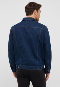 Ciemnoniebieska kurtka dżinsowa o klasycznym kroju, z widocznym przeszyciem i guzikami, z kołnierzem i dwiema bocznymi kieszeniami.