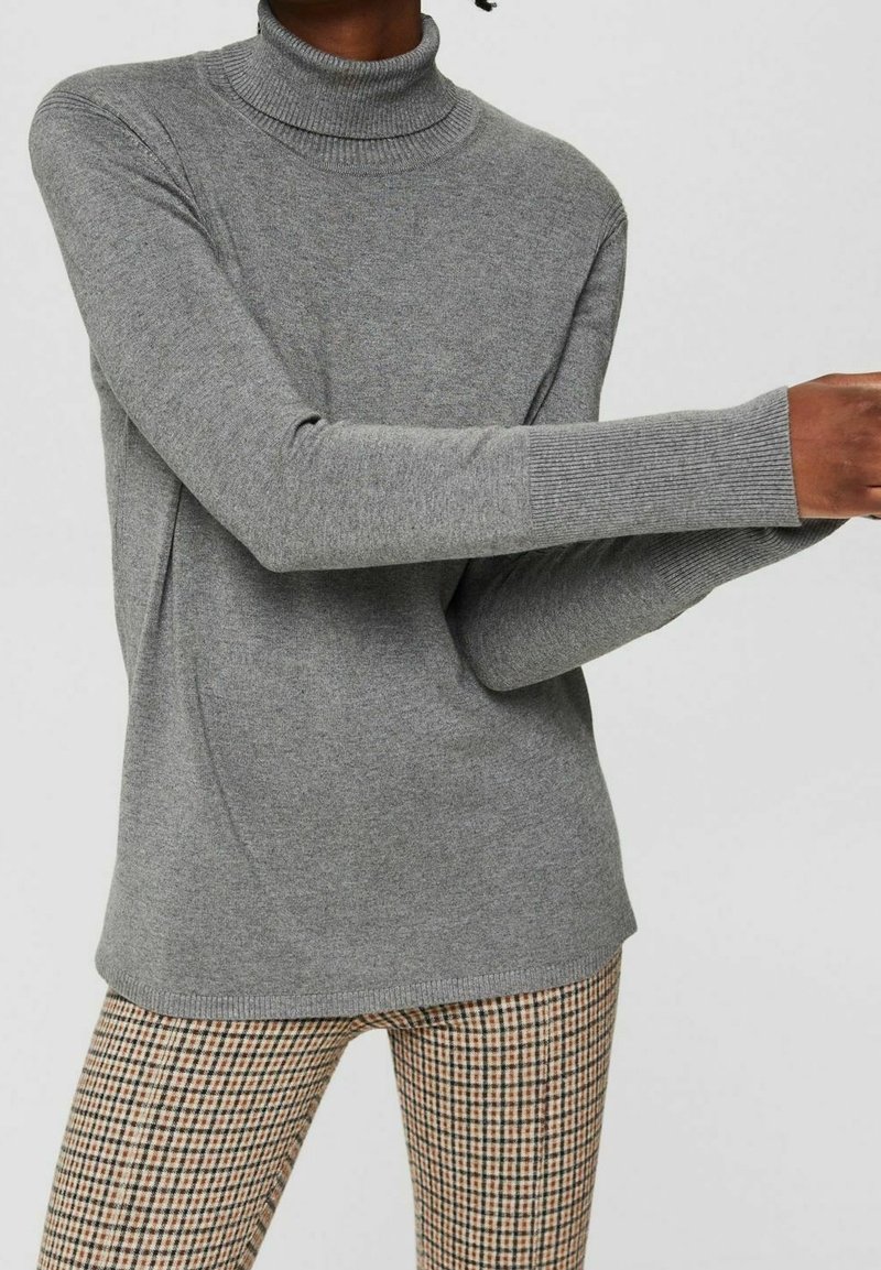 Grijze coltrui van een zachte gebreide stof met lange mouwen en geribbelde manchetten, gecombineerd met een geruite broek.