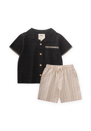 Schwarzes Kurzarmhemd mit Holzknöpfen und Tasche, kombiniert mit beigen Shorts mit vertikalen Streifen und elastischem Bund.