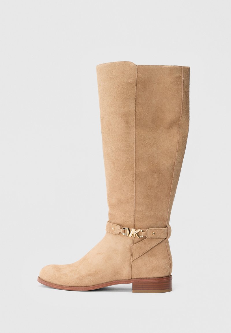 Polven yläpuolelle ulottuva beige mokkanahkainen saapas pyöreällä kärjellä, kultaisilla metalliosilla ja matalalla pinottulla korolla. Saappaassa on sivusaumassa ompeleita.