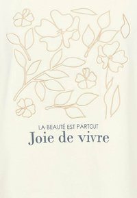 Cremefarbener Stoff mit hellbrauner Blumenstickerei und Text. Das Design umfasst verschiedene Blumen und Blätter mit dem Schriftzug „Joie de vivre.“