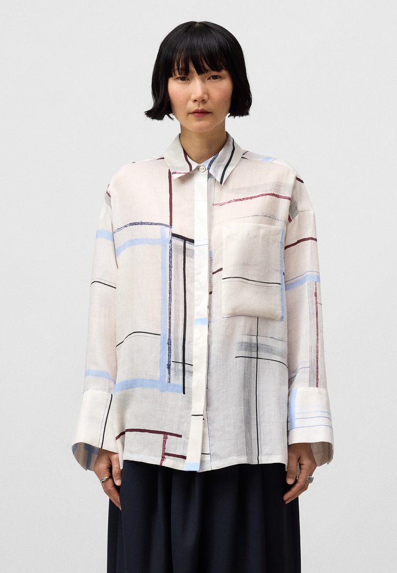 Camicia con bottoni in tessuto leggero con un motivo a griglia composto da linee rosse, blu e nere. Include una tasca sul petto e maniche ampie.