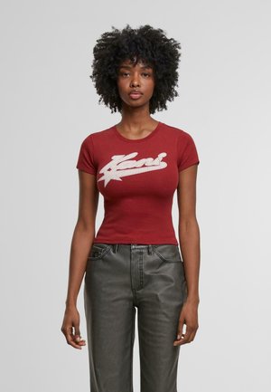 T-shirt rouge ajustée à manches courtes avec logo graphique blanc. Associée à un jean gris foncé légèrement ample avec poches.