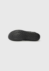 Sole di scarpe in gomma nera con un battistrada decorato, dotata di un bordo leggermente rialzato e una superficie testurizzata per migliorare la trazione e la durata.