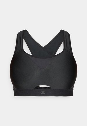 Brassière de sport noire avec bretelles croisées dans le dos, texture lisse, et un détail découpé subtil à l'avant. Logo présent sur la bande.