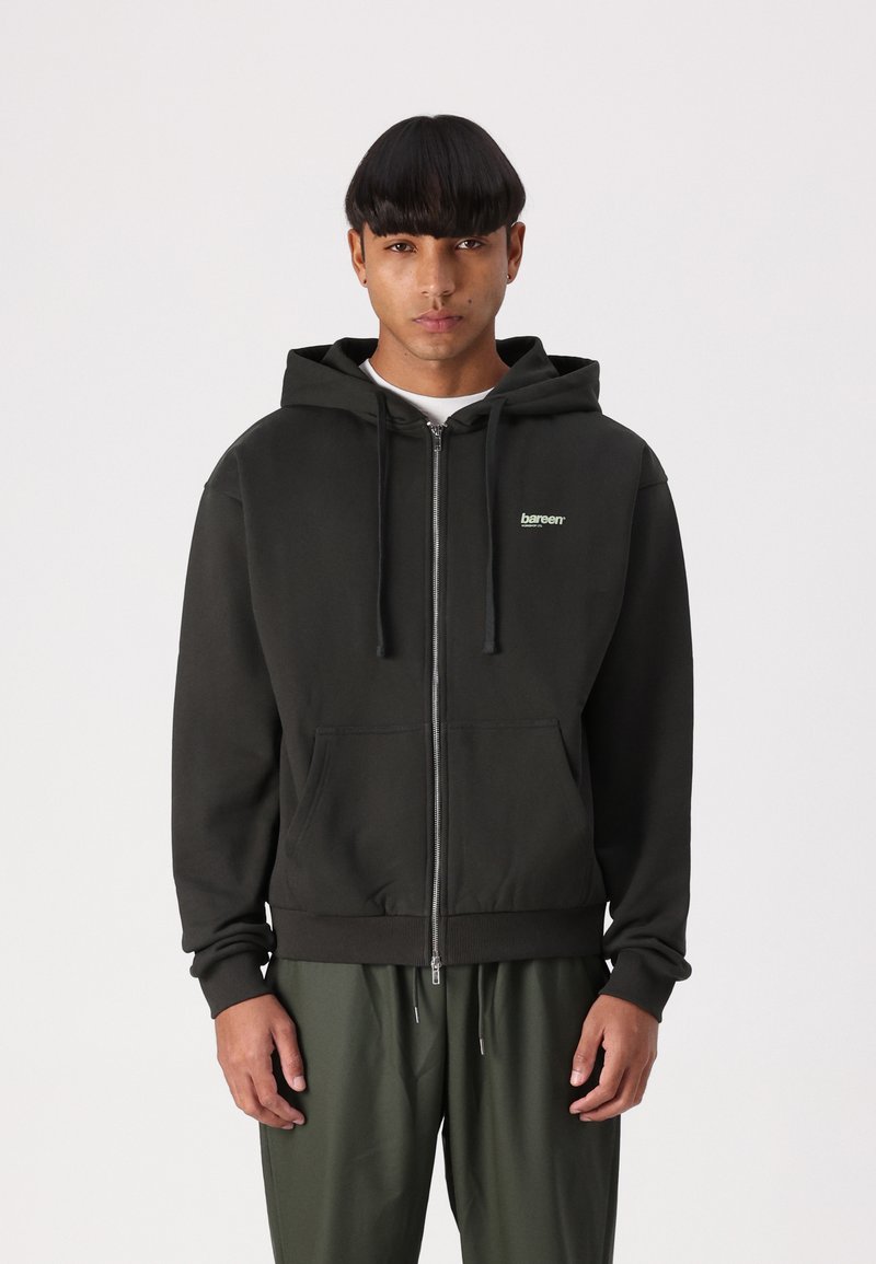 Mørkegrønne zip-up hættetrøje med kængurulomme, snoretræk til hætten, ribbet manchetter og lille logo detalje på venstre bryst.