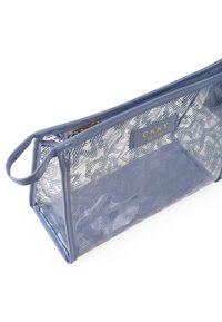 Neceser transparente azul con patrón interior geométrico, cierre de cremallera y logotipo de DKNY en dorado. Cuenta con un asa en un lado.