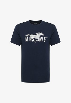 Tumši zila kokvilnas T-krekls ar lielu baltu grafiku, kurā attēlots jājošs zirgs, un vārds "MUSTANG" bolderakstā zem tā. Īsas piedurknes.