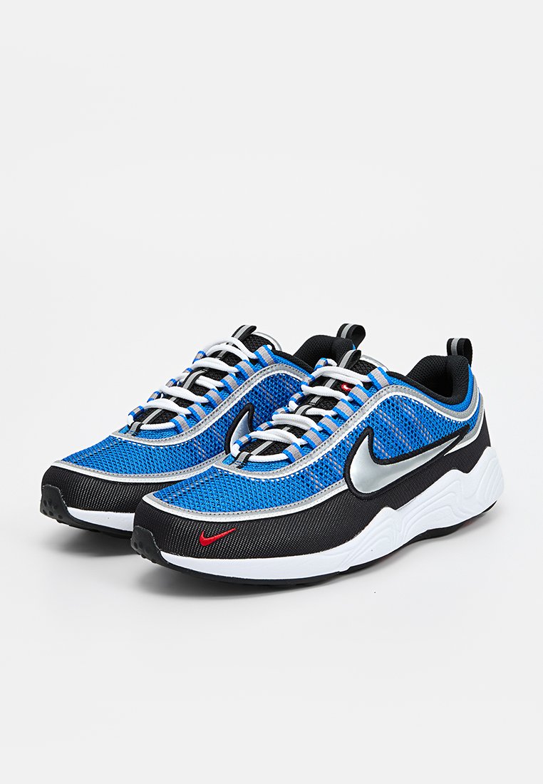 Zapatillas de malla azul con detalles en negro y blanco, con un logo plateado de Nike, suelas blancas y un detalle rojo contrastante en el diseño.