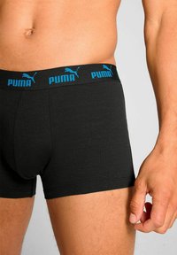 Black boxer briefs made from soft fabric, featuring a wide black waistband with blue "PUMA" logo and emblem.