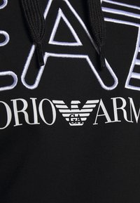 Felpa nera con testo e logo ricamati in bianco. Il design comprende lettere in grassetto ed un emblema alato. Tessuto morbido e strutturato.