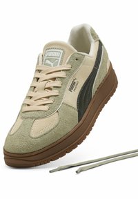 Sneakers in pelle scamosciata con pannelli beige e verdi, suola in gomma marrone, dettagli testurizzati e lacci abbinati. Logo PUMA sulla linguetta.