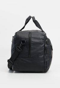 Černá nylonová taška s kulatým tvarem, zipovými přihrádkami, držadly a nastavitelným ramenním popruhem. Hladký povrch s logem.