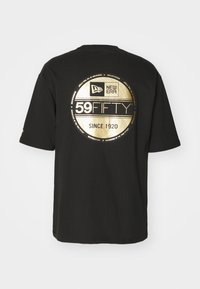 T-shirt in cotone nero con un grande logo circolare dorato sulla schiena con la scritta "59FIFTY" e "dal 1920". Maniche corte, collo rotondo.