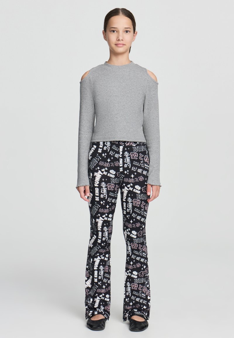 Szary, długi rękaw top z wycięciami na ramionach, zestawiony z czarnymi spodniami w dzwony z mieszanym graficznym nadrukiem w białym i różowym kolorze.