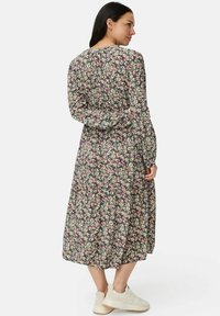 Bloemenjurk met lange mouwen in een donkere achtergrond met kleine roze en witte bloemen, een ontspannen pasvorm en een vloeiende mid-lengte zoom.