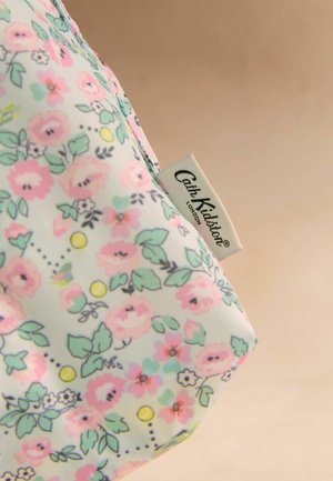 Saculeț mic din material textil cu model floral pastel roz și verde și o etichetă Cath Kidston London pe fundal bej.