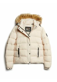 Padded creamowa kurtka z futrzanym kapturem, zamykanymi kieszeniami i czarnymi akcentami. Teksturowany materiał o pikowanej strukturze.