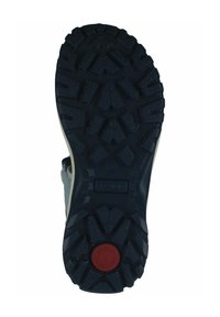 Suela de zapato con un material de goma negra, grueso y resistente. Presenta profundos surcos, un acento circular rojo y una etiqueta en el centro marcada como "FLEXIBLE".