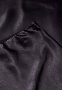 Schwarzer Satin-Stoff mit glatter Textur, der einen leichten Glanz und subtile Falten aufweist. Die Kanten sind sauber verarbeitet und betonen ein elegantes Design.