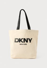 Plátená taška na rameno v béžovej farbe s čiernym potlačeným textom DKNY a NEW YORK. Má čierne ramenné popruhy a pevný tvar.