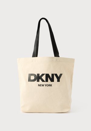 Beige kangaskassi, jossa mustat DKNY- ja NEW YORK -tekstipainatukset. Varustettu mustilla olkahihnoilla ja jämäkällä muodolla.