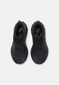 Chaussures de sport noires avec une tige texturée, un bout rond et un laçage à l'avant. Elles disposent d'une semelle rembourrée et de subtils accents gris.