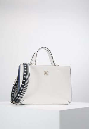 Biała skórzana torebka z dwoma krótkimi uchwytami oraz odpinanym czarno-białym paskiem na ramię z wzorami gwiazd.