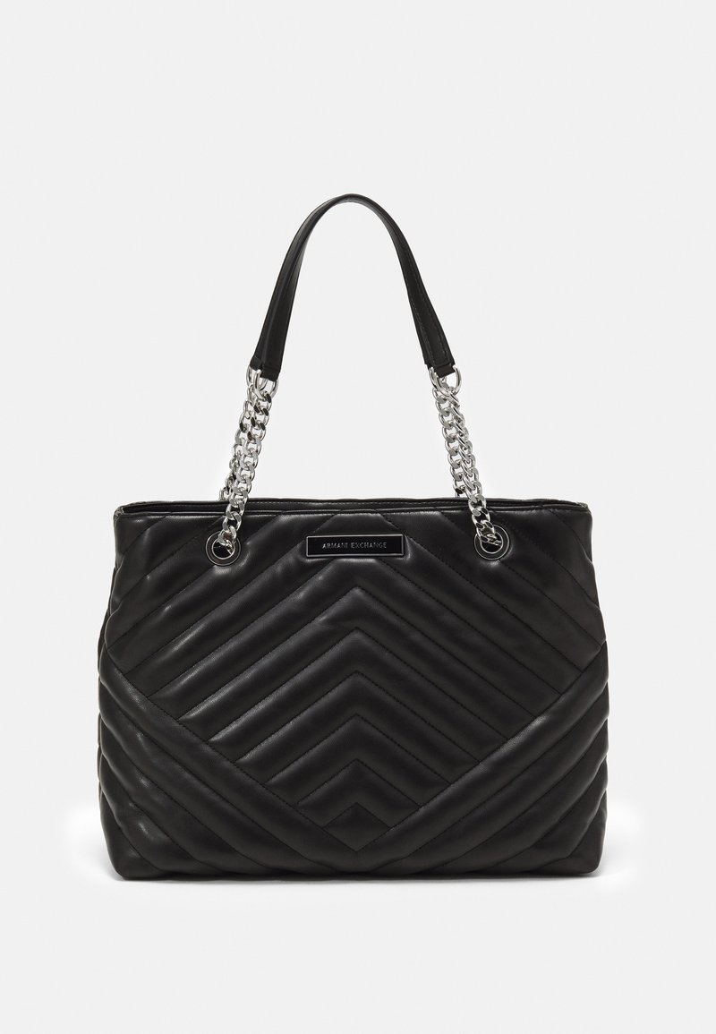 Czarna pikowana torba typu tote z wzorem w jodełkę, z sylwetkowymi uchwytami złożonymi z srebrnych łańcuchów oraz czarnym skórzanym paskiem na ramię. Z przodu umieszczona jest plakietka z logo.