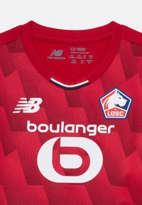 Piros sportruházat texturált mintával. Fehér logóval, "boulanger" szöveggel és kék-piros pajzsot ábrázoló csapatcímerrel rendelkezik. Kerek nyakú dizájn.