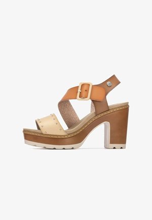 Sandalia de tacón en tono bronceado y crema con diseño de tiras cruzadas, cierre de hebilla, tachuelas y plantilla texturizada, con tacón grueso tipo plataforma.
