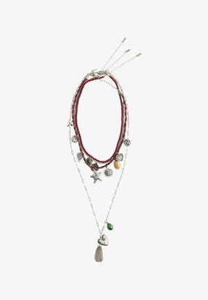 Layered necklace with red beads, silver chains, and various charms including stars, hearts, a sun, a yellow oval stone, and a green teardrop stone.
