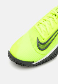 Neon gul atletiksko med en tekstureret overdel, der har et sort swoosh-logo og en mønstret gummisål. Snørebånd i matchende gul.