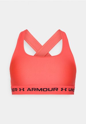 Stanik sportowy w jasnym koralowym kolorze, z gładką teksturą, krzyżowym designem na plecach oraz czarną elastyczną taśmą z logo "Under Armour".