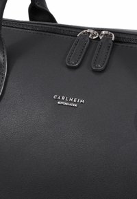 Melnā vegāna ādas somiņa ar diviem rāvējslēdzējiem, tekstūrētu virsmu un sudraba logotipa akcentu ar zīmola nosaukumu "CARNLHEIM COPENHAGEN".