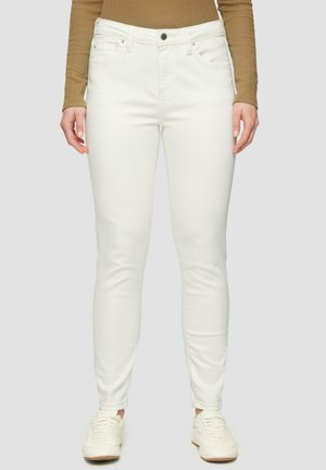 Weiße schmale Jeans mit glatter Textur, fünf Taschen und einem Knopfverschluss. Kombiniert mit weißen Sneakers und einem braunen Langarmshirt.