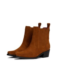 Bottines en suède marron avec un bout pointu, des panneaux latéraux texturés et un petit talon carré. Dotées de languettes pour un enfilage facile.