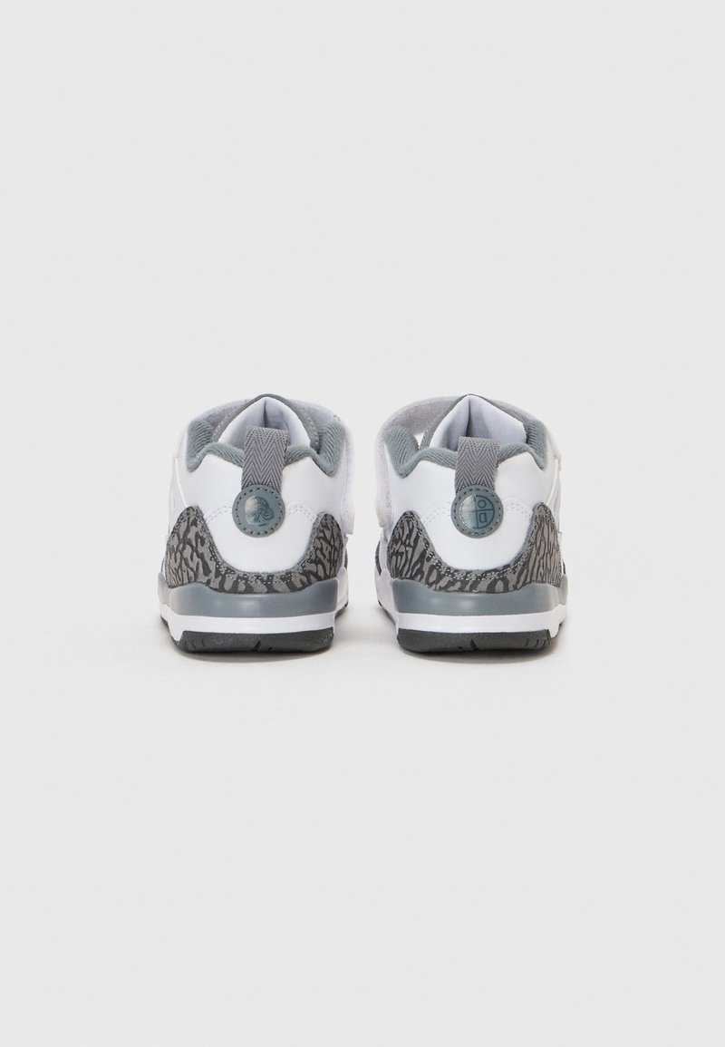 Witte sportieve schoenen met gestructureerde grijze accenten, voorzien van een patroon op de hiel en een grijze trekband. De zool is zwart met een profielontwerp.