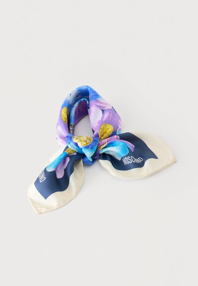 Foulard en soie noué avec un motif floral bleu et violet et des accents dorés, avec des bords crème et le logo Moschino aux coins.
