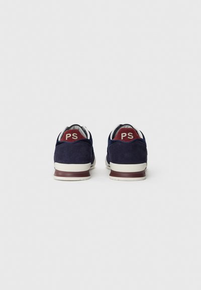 Sneakers in camoscio blu navy con una suola intermedia bianca, dettagli bordeaux sul tallone e un logo sul retro. Texture liscia e design arrotondato.