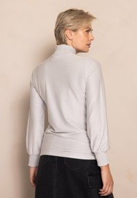 Light gray long-sleeve top with a smocked high collar and puffed sleeves, featuring a smooth, shiny texture and fitted hem.