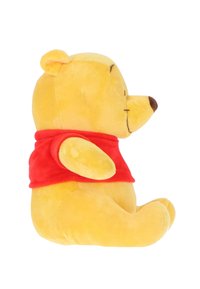Yellow plush teddy bear with a round face, wearing a red shirt. Soft texture, arms outstretched, and a small, brown nose. Side view.